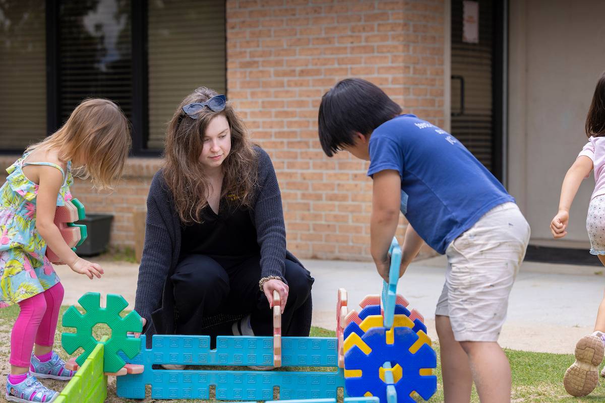LSU Preschool students play outside with a teacher