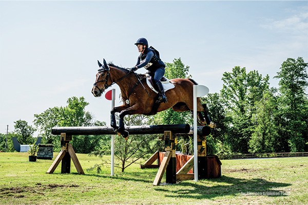 Dr. Erin Roof-Wages jumping a fence on a horse as part of a competition